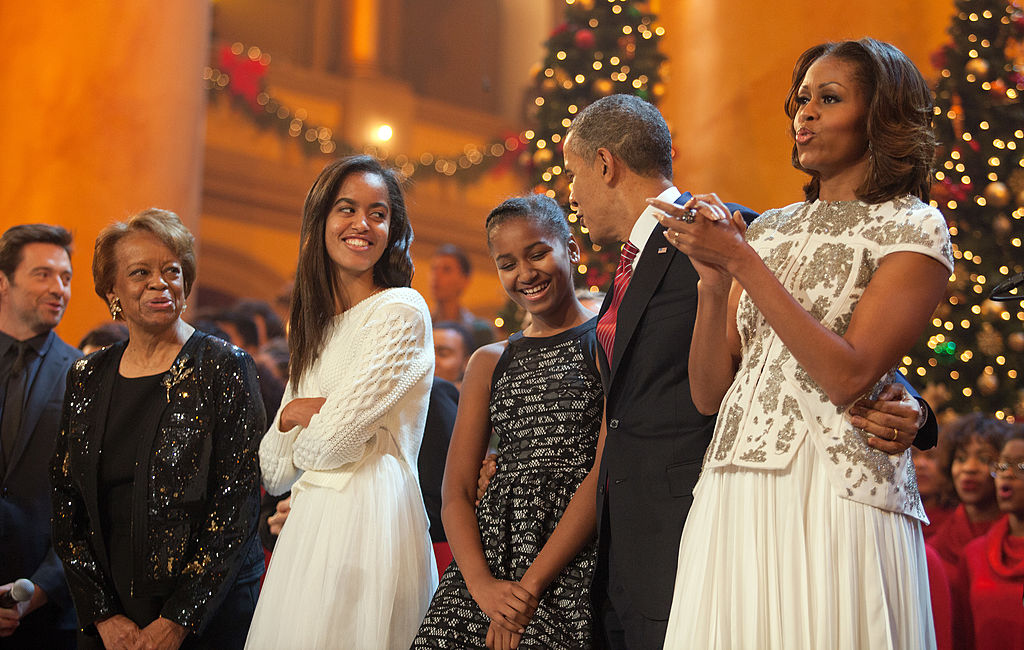 WASHINGTON, DC - DECEMBER 15: U.S. President Barack Obama and first lady Michelle Obama, along with daughters Malia (left) and Sasha, sing during the finale of TNT's "Christmas in Washington" on December 15, 2013 in Washington, DC. The program benefits the Children's National Health System. Also shown are the president's mother-in-law, Marian Robinson, and the program's host, actor Hugh Jackman. (Photo by Martin H. Simon-Pool/Getty Images)