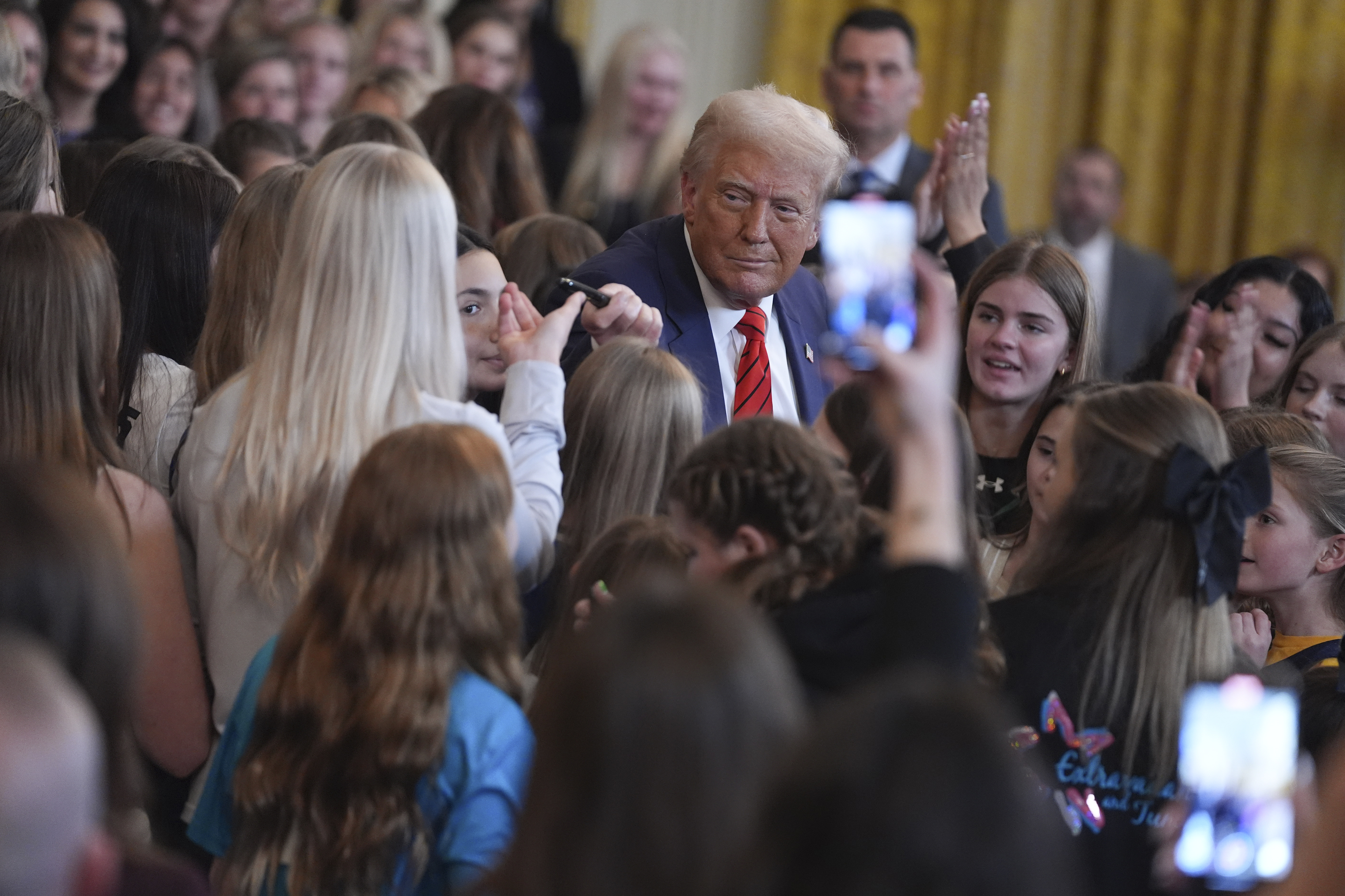 President Donald Trump hands a pen to Riley Gaines after signing an executive order barring transgender female athletes from competing in women's or girls' sporting events, in the East Room of the White House, Wednesday, Feb. 5, 2025, in Washington.(AP Photo/ Evan Vucci)