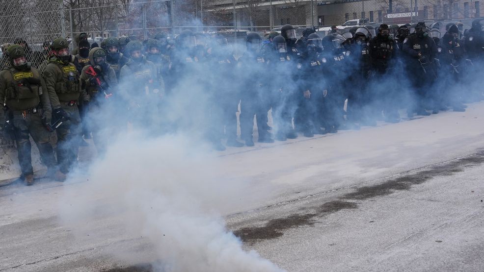 Federal immigration officers stand outside Bishop Henry Whipple Federal Building as tear gas is deployed Thursday, Jan. 15, 2026, in Minneapolis. (AP Photo/Adam Gray)